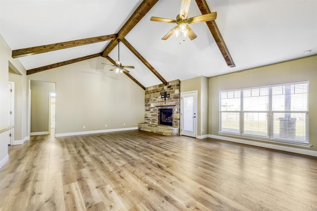 785 Schneider Road Howe, TX 75459 - Photo 3 of 40 Unfurnished living room featuring a stone fireplace, light wood-style floors, and a ceiling fan