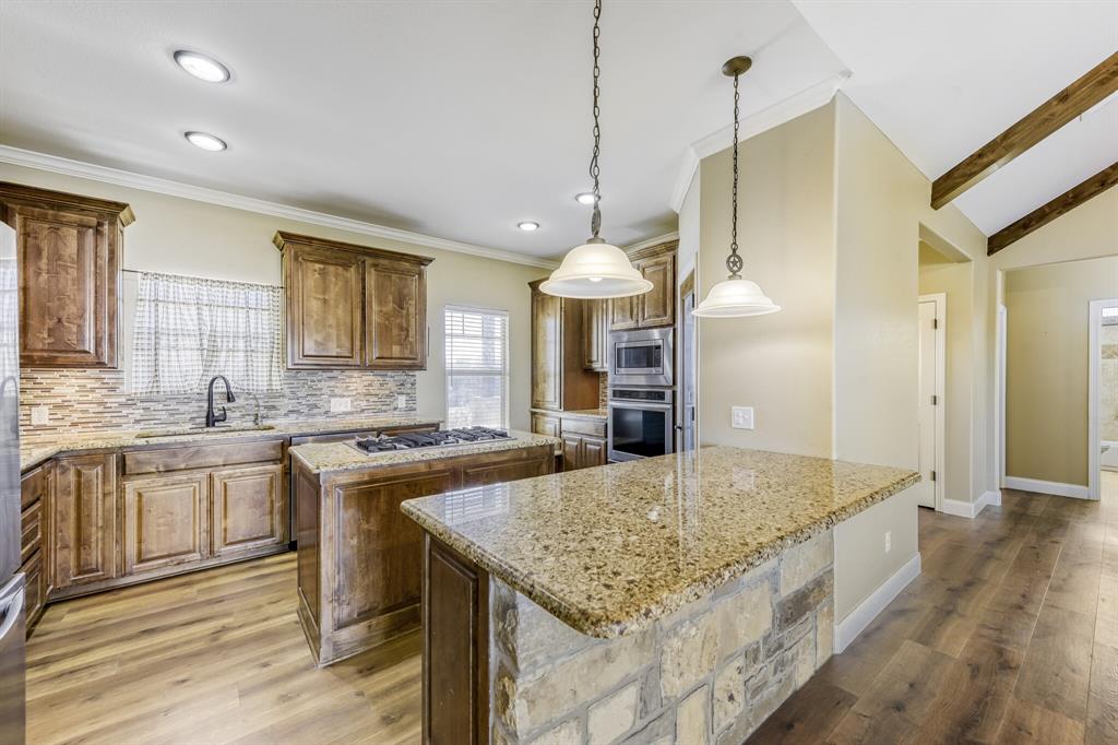 785 Schneider Road Howe, TX 75459 - Photo 8 of 40 Kitchen with light wood-type flooring, pendant lighting, light stone countertops, a kitchen island, and wood finish cabinets