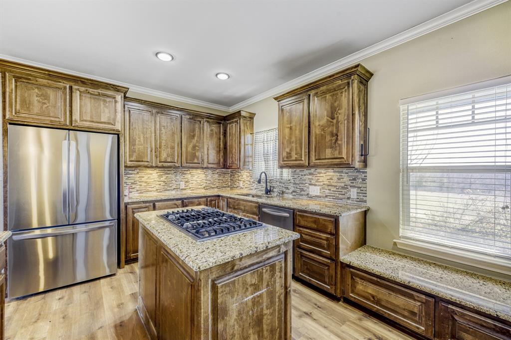 785 Schneider Road Howe, TX 75459 - Photo 9 of 40 Kitchen featuring stainless steel appliances, ornamental molding, light wood-type flooring, light stone countertops, and a kitchen island