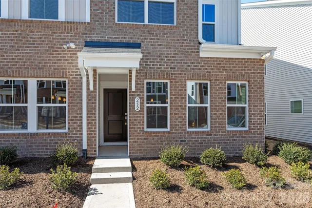 a front view of a brick house with a yard and potted plants