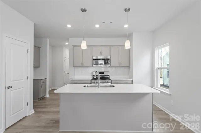 a view of a kitchen with kitchen island a sink stainless steel appliances and cabinets