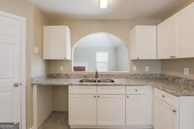 a kitchen with granite countertop white cabinets and a sink