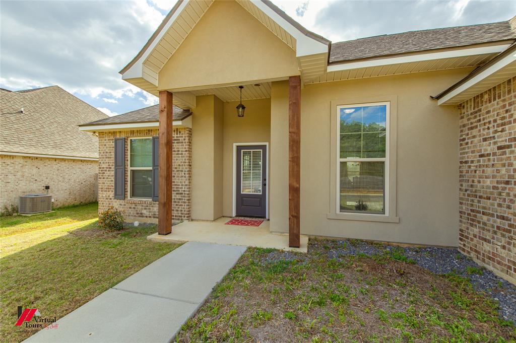 331 Hummingbird Lane Princeton, LA 71067 - Photo 30 of 34 Entrance to property with a lawn, brick siding, stucco siding, roof with shingles, and covered porch