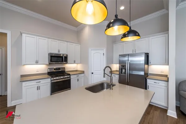 a large kitchen with a sink stainless steel appliances and cabinets