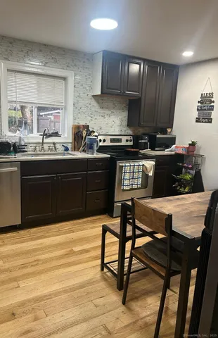 a kitchen with stainless steel appliances granite countertop a stove top oven a sink dishwasher and cabinets with wooden floor