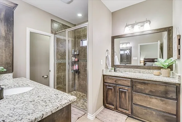 a bathroom with a granite countertop sink a mirror and a shower