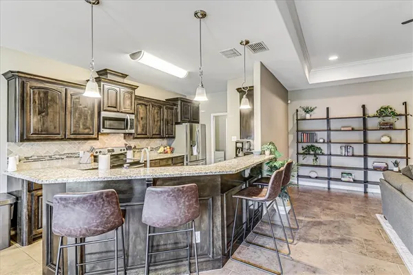 a dining hall with stainless steel appliances kitchen island a table and chairs