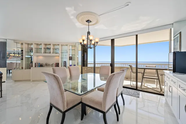 a dining room with furniture a chandelier and large windows