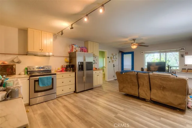 a kitchen with stainless steel appliances kitchen island granite countertop a refrigerator a stove a sink dishwasher and a fireplace with wooden floor