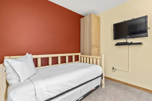 a bedroom with a bed table and flat screen tv