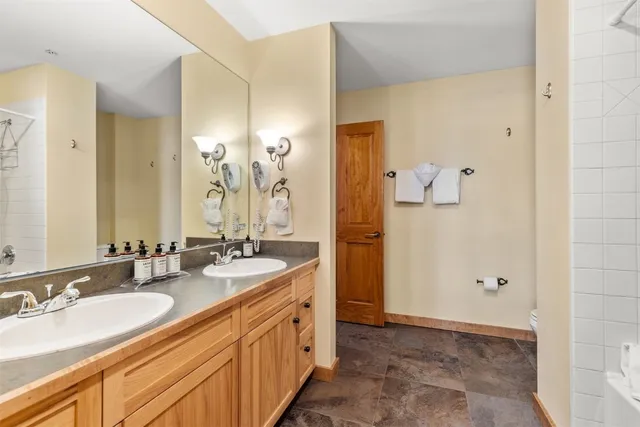 a bathroom with double vanity sinks a toilet a mirror and shower