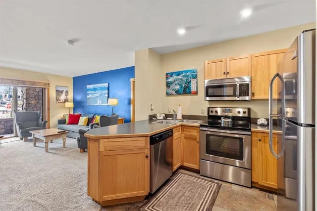 a kitchen with stainless steel appliances granite countertop a stove top oven a sink dishwasher a dining table and chairs with wooden floor