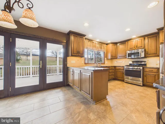 a kitchen with stainless steel appliances granite countertop a stove top oven a sink a dining table and chairs with wooden floor