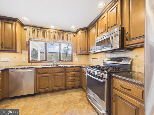 a kitchen with stainless steel appliances granite countertop a stove a sink and a microwave