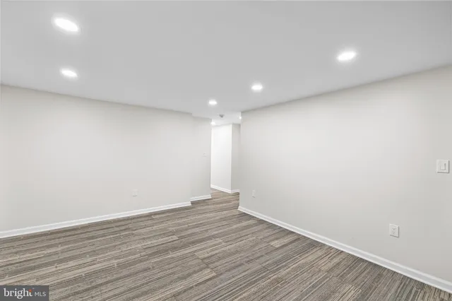 a view of an empty room with wooden floor and a bathroom