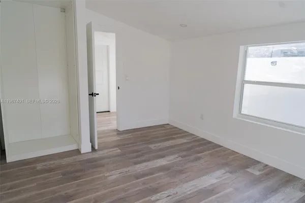 a view of an empty room with wooden floor and a window