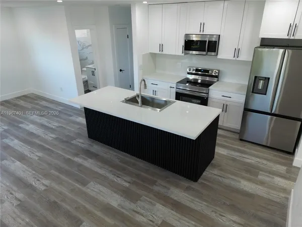 a kitchen with stainless steel appliances a sink a stove a microwave and wooden floor