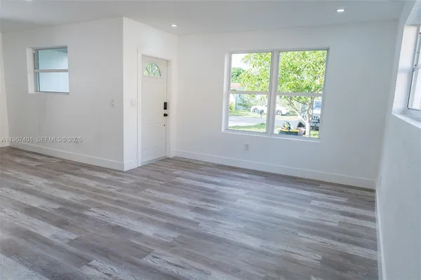 a view of an empty room with wooden floor and a window