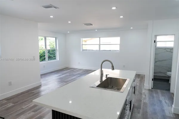 a kitchen with kitchen island a sink appliances wooden floor and a window