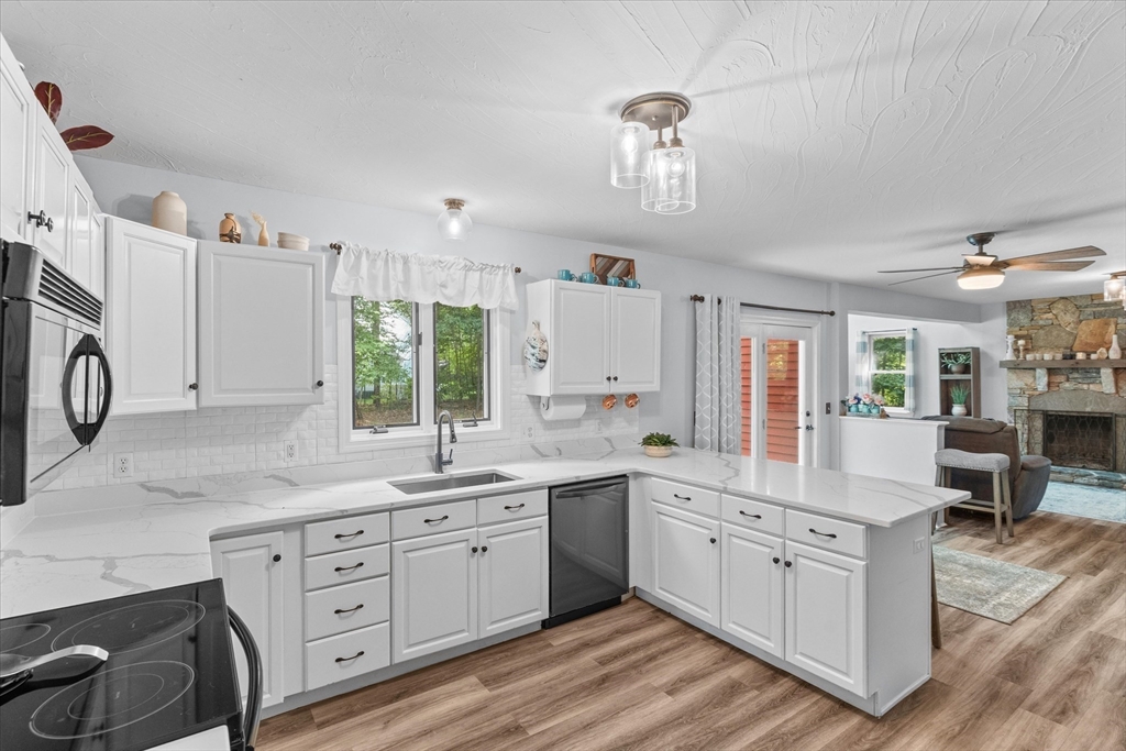 a kitchen with a sink dishwasher a stove and white cabinets with wooden floor