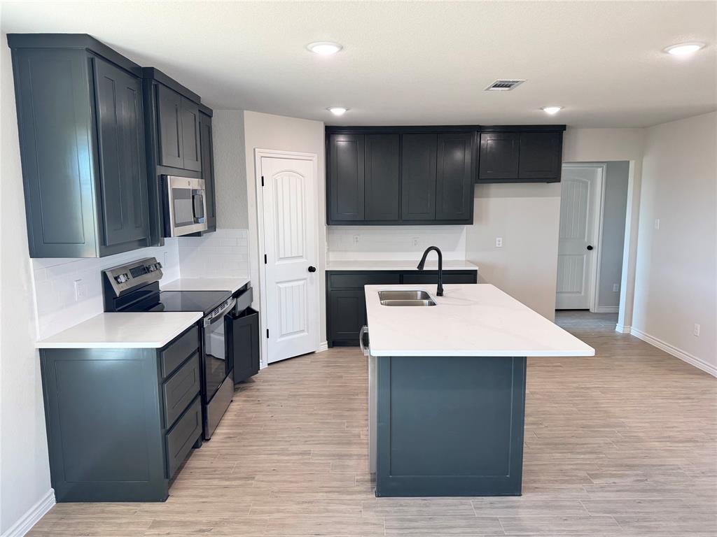 760 Smith Road Springtown, TX 76082 - Photo 5 of 9 a kitchen with stainless steel appliances a sink dishwasher stove refrigerator and cabinets with wooden floor