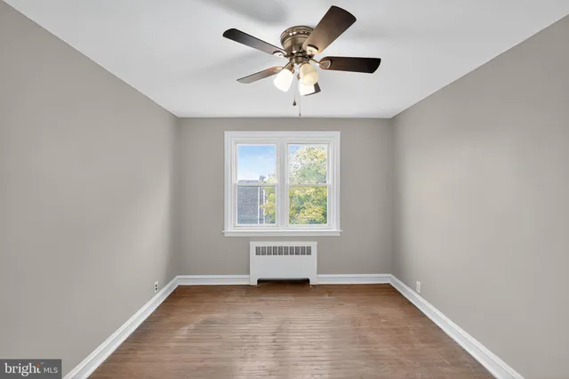 an empty room with a window and a fan