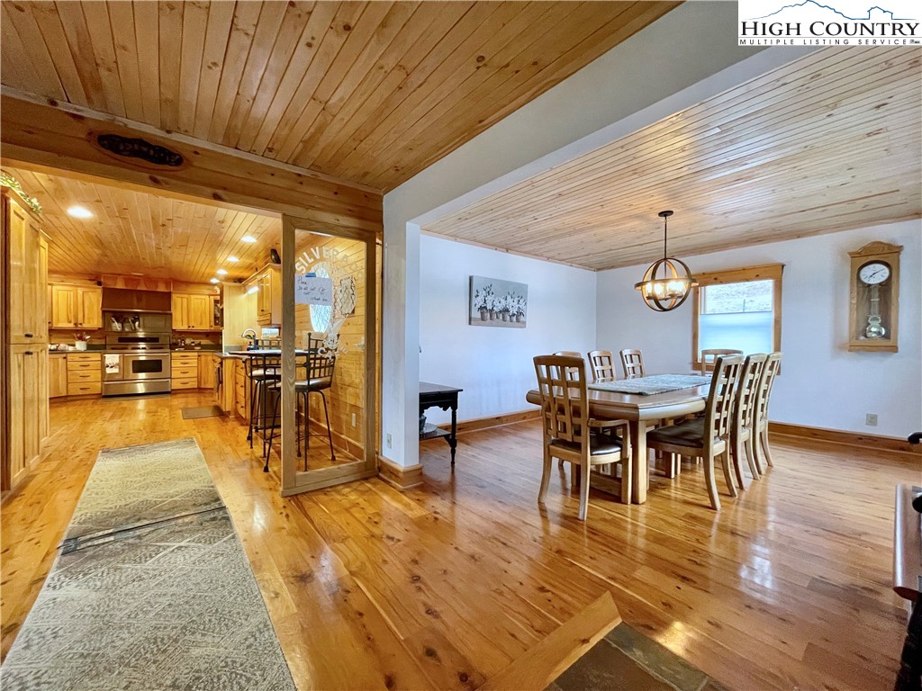 175 Woods Road Boone, NC 28607 - Photo 16 of 50 a dining room with furniture wooden floor a rug and a kitchen view