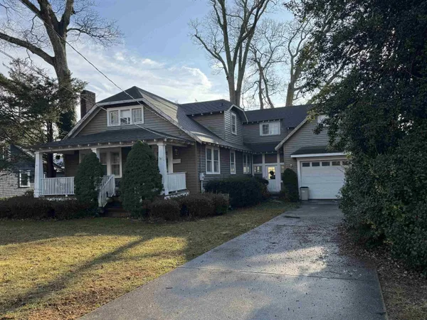 a front view of a house with a garden and trees