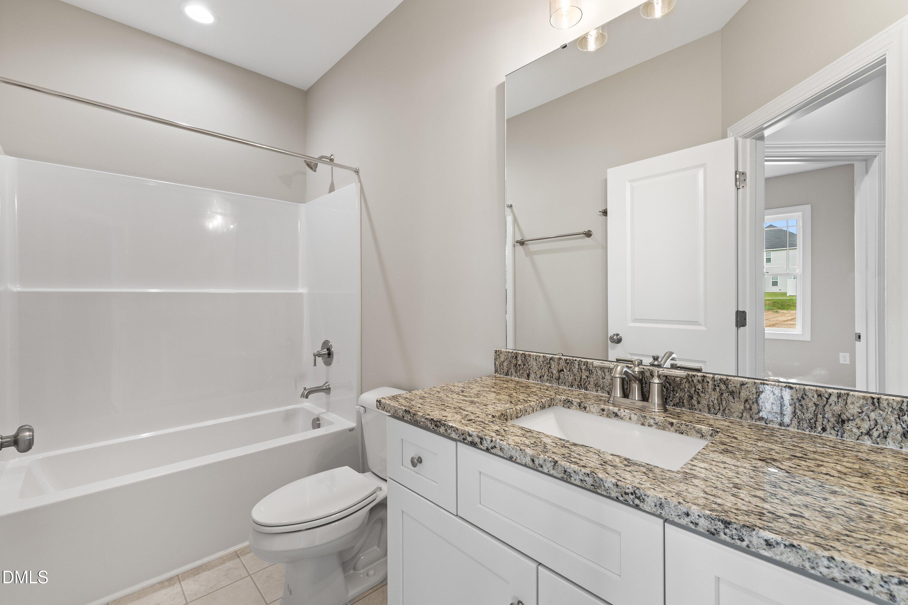 1115 Nor-Am Road Pikeville, NC 27863 - Photo 19 of 40 a bathroom with a granite countertop toilet a sink and a bathtub