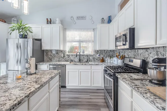 a kitchen with stainless steel appliances granite countertop a sink stove and cabinets