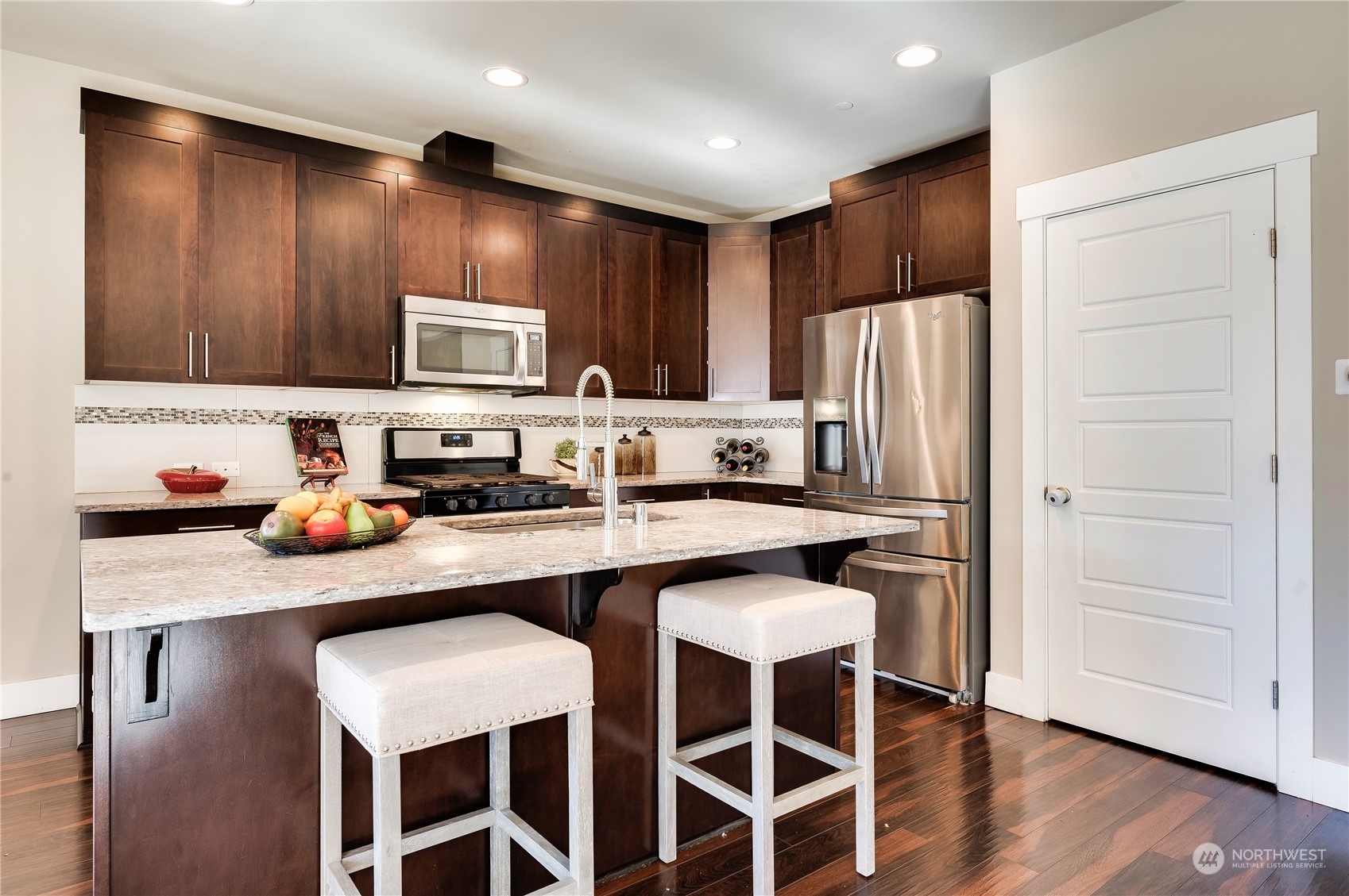 14372 3rd Circle Northeast Duvall, WA 98019 - Photo 11 of 34 a kitchen with stainless steel appliances kitchen island granite countertop a refrigerator a stove a sink and a oven with wooden floor