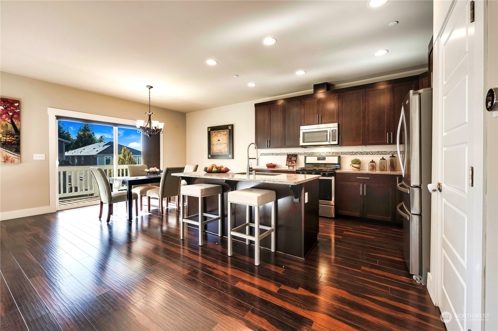 14372 3rd Circle Northeast Duvall, WA 98019 - Photo 9 of 34 a open kitchen with stainless steel appliances granite countertop a stove top oven a sink dishwasher a dining table and chairs with wooden floor