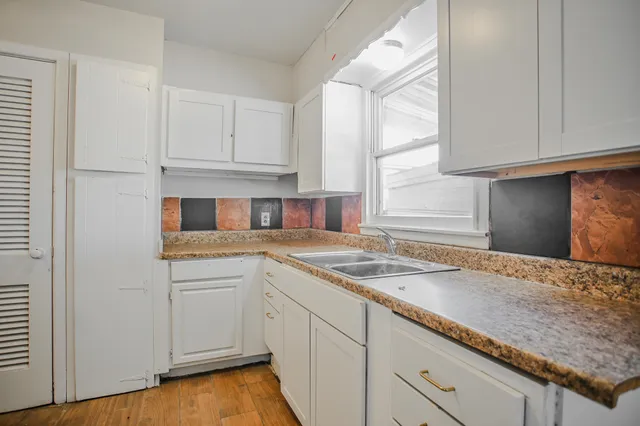 a kitchen with granite countertop white cabinets and a sink