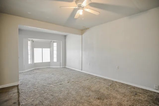 an empty room with fan and windows