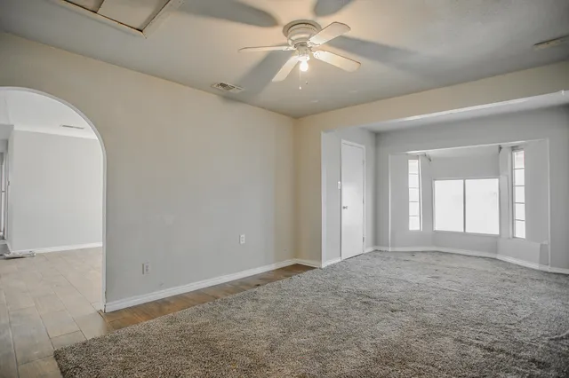 an empty room with a ceiling fan and carpet