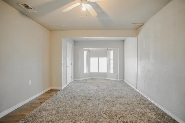 an empty room with a ceiling fan and a window