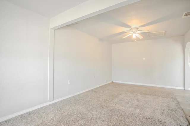 an empty room with a window and a chandelier fan