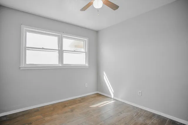 an empty room with a fan & a window