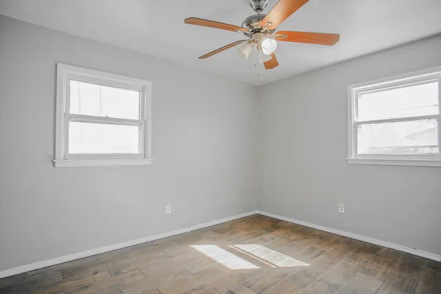 an empty room with a ceiling fan and wooden floor