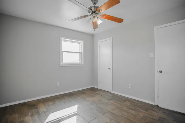 an empty room with windows and fan