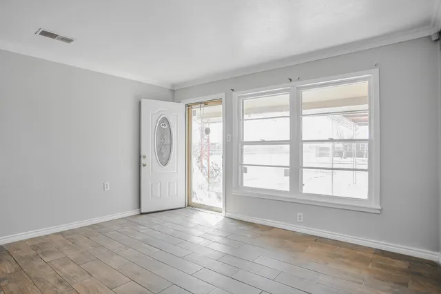 a view of an empty room with wooden floor and a window