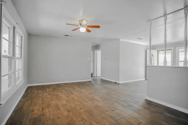 a view of an empty room with wooden floor and a window