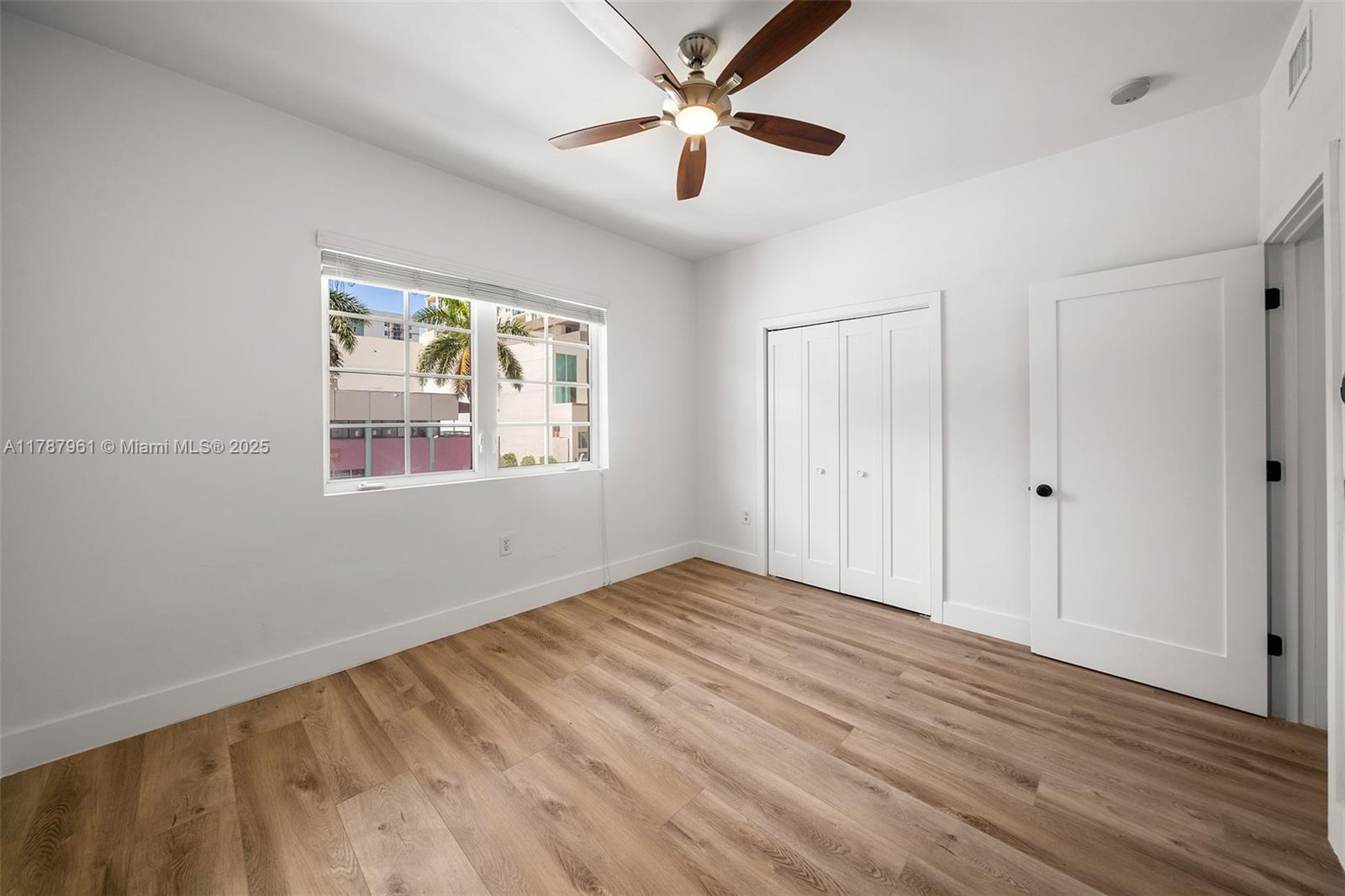 2411 Biscayne Boulevard, Unit 2 Miami, FL 33137 - Photo 13 of 25 an empty room with wooden floor chandelier fan and windows