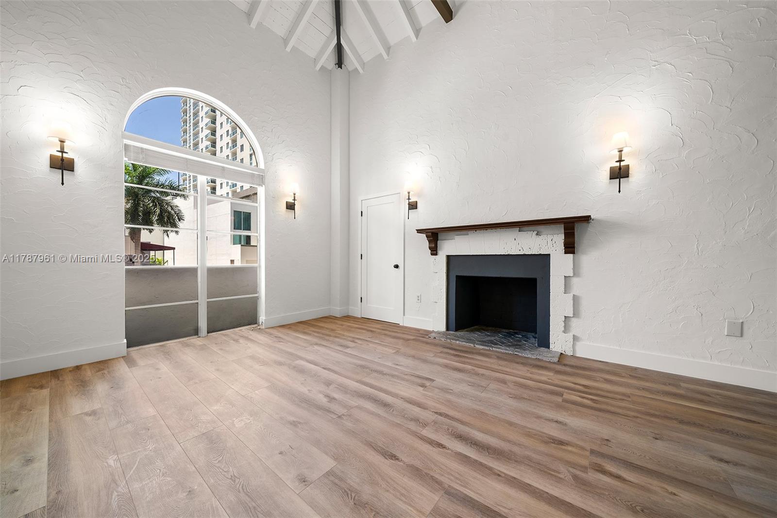 2411 Biscayne Boulevard, Unit 2 Miami, FL 33137 - Photo 17 of 25 an empty room with a fireplace and a chandelier