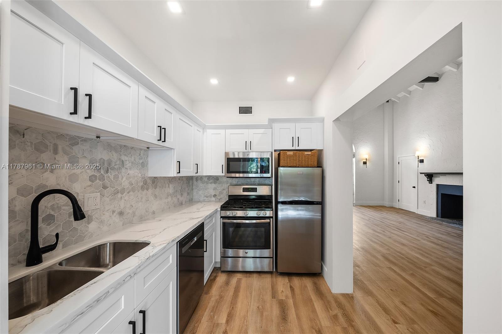 2411 Biscayne Boulevard, Unit 2 Miami, FL 33137 - Photo 6 of 25 a kitchen with stainless steel appliances a refrigerator sink and wooden cabinets
