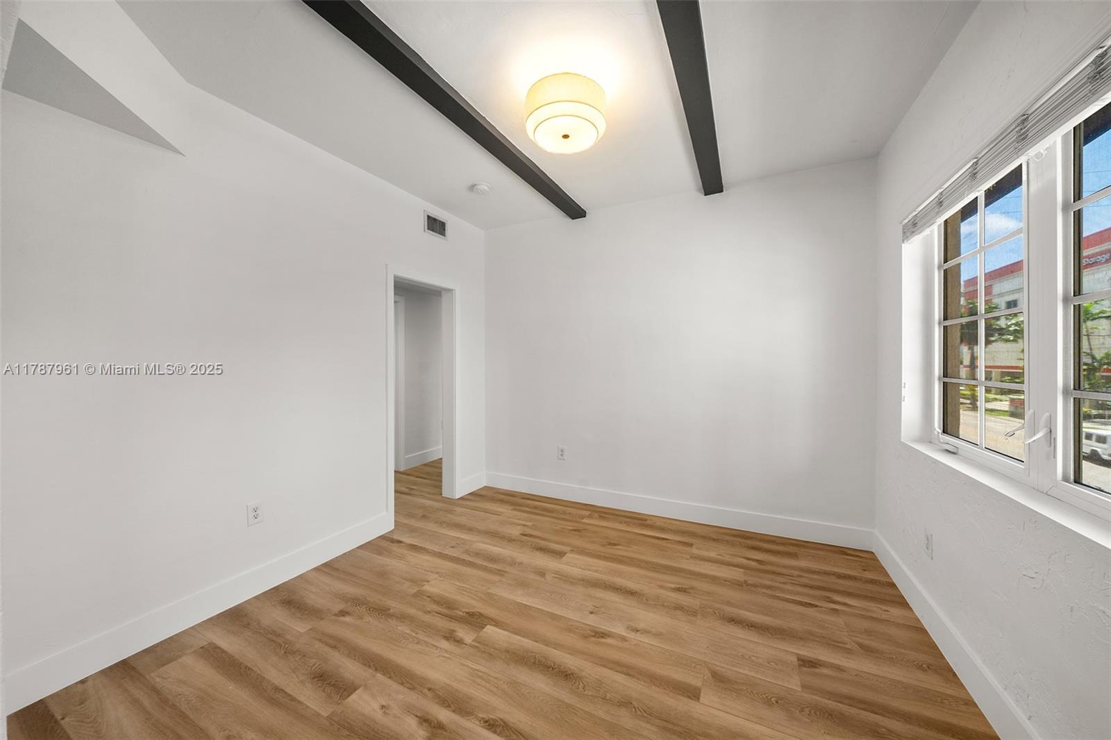 2411 Biscayne Boulevard, Unit 2 Miami, FL 33137 - Photo 7 of 25 a view of an empty room with wooden floor and a window