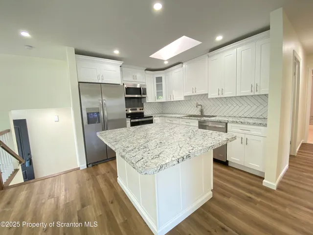 a kitchen with kitchen island a sink stove and refrigerator