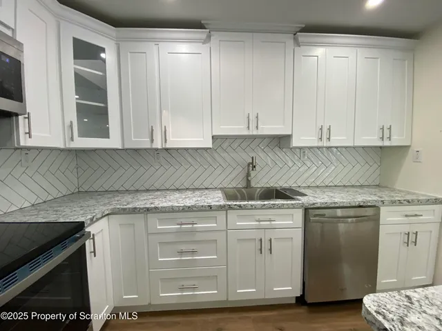 a kitchen with stainless steel appliances granite countertop a stove and a white cabinets
