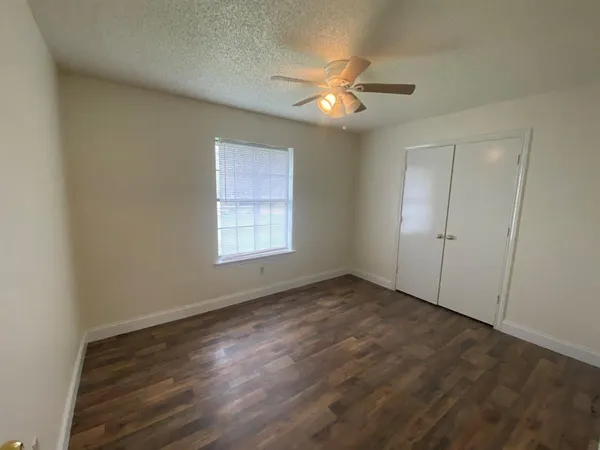 an empty room with wooden floor fan and windows