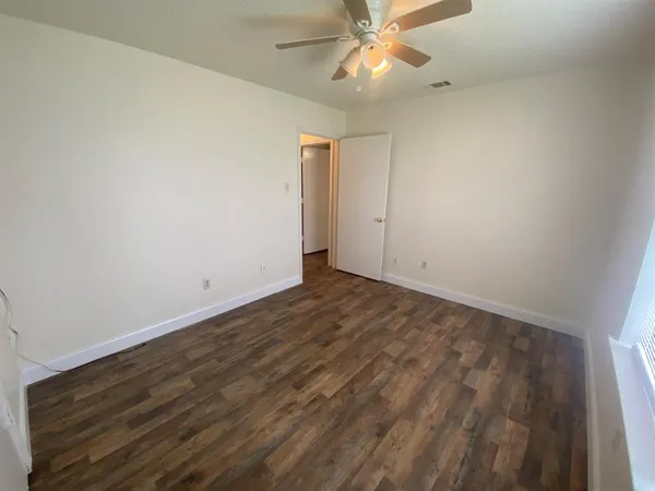 an empty room with a ceiling fan and wooden floor